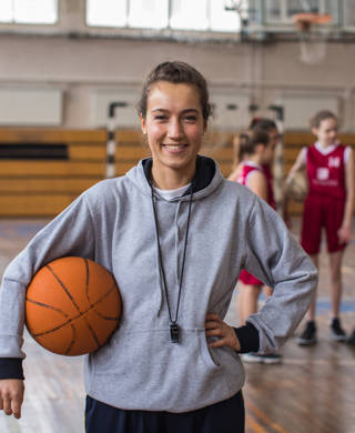 Vrouwelijke basketbalcoach met een jong team in sporthal